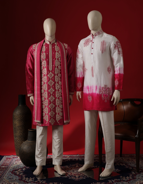 Two mannequins dressed in vibrant traditional men's kurta sets — one in a rich red embroidered sherwani-style kurta with cream churidar, and the other in a white and pink gradient kurta with subtle embroidery, styled against a red backdrop with ethnic decor.